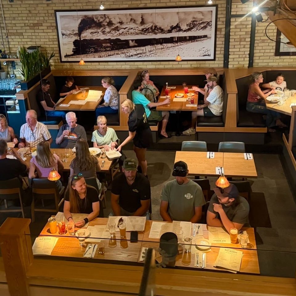 Overhead view of a bustling restaurant dining room with many patrons seated at tables and booths.